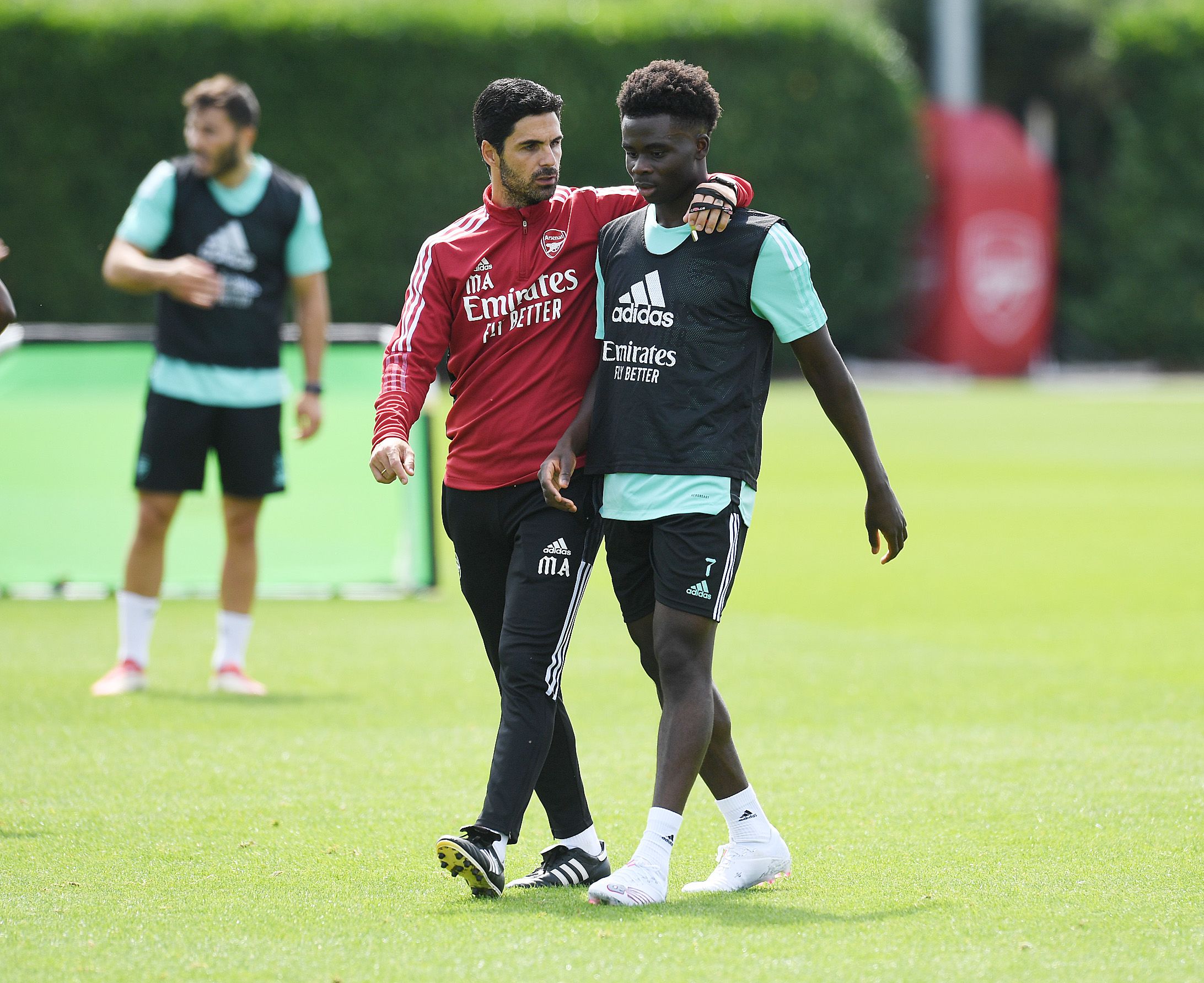 Mikel Arteta puts his arm around Bukayo Saka during a training session in August 2021