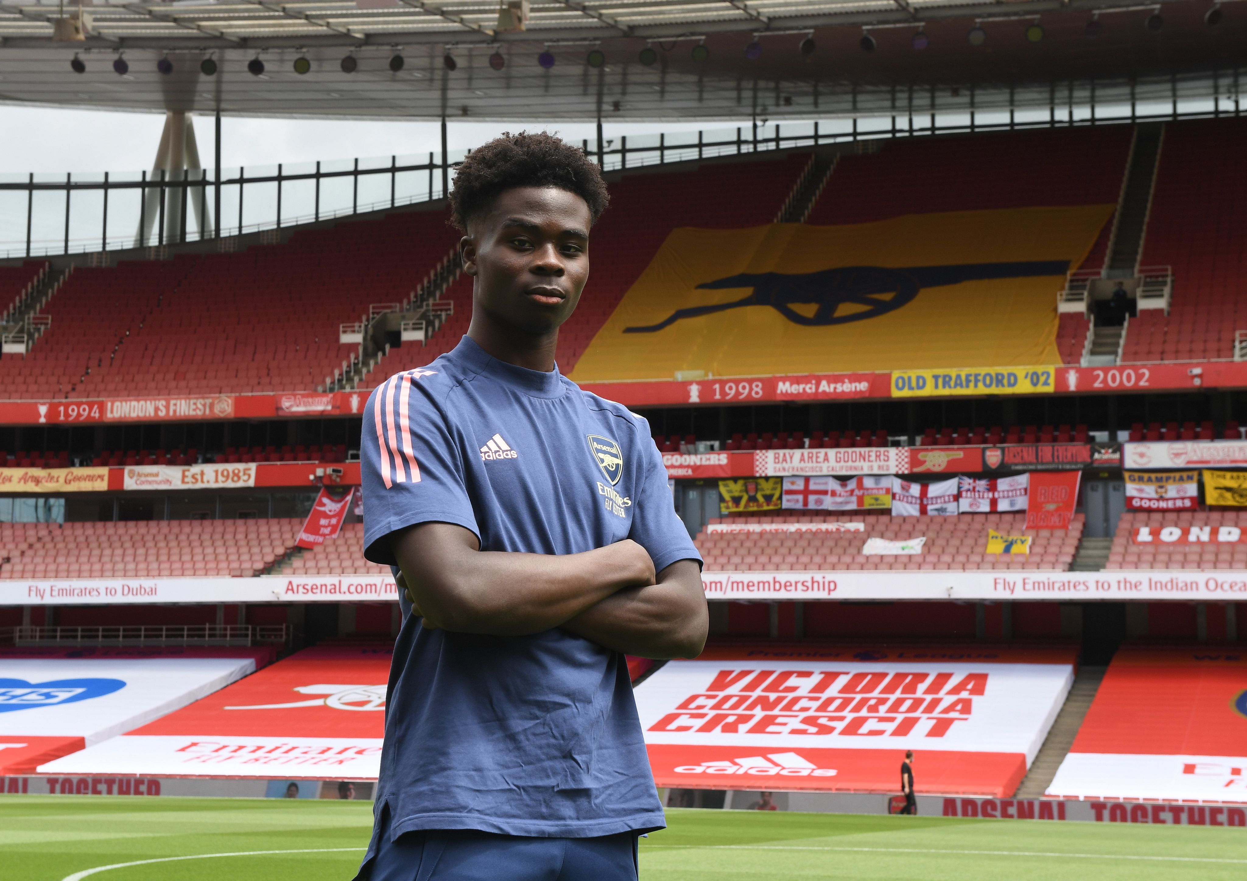 Bukayo Saka poses on the pitch at Emirates Stadium after signing a new contract in 2020