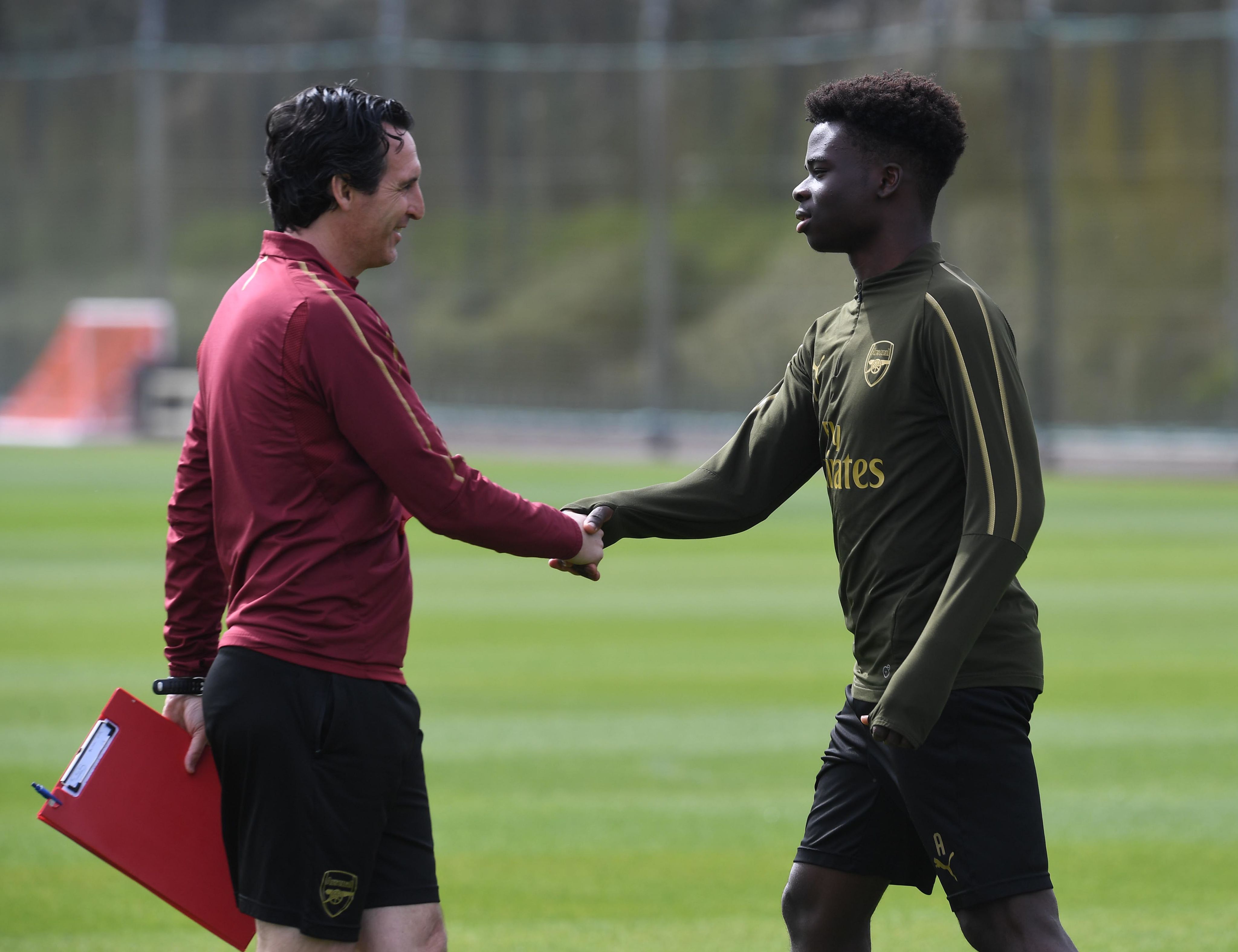 Unai Emery shakes hands with Buyako Saka before a training session