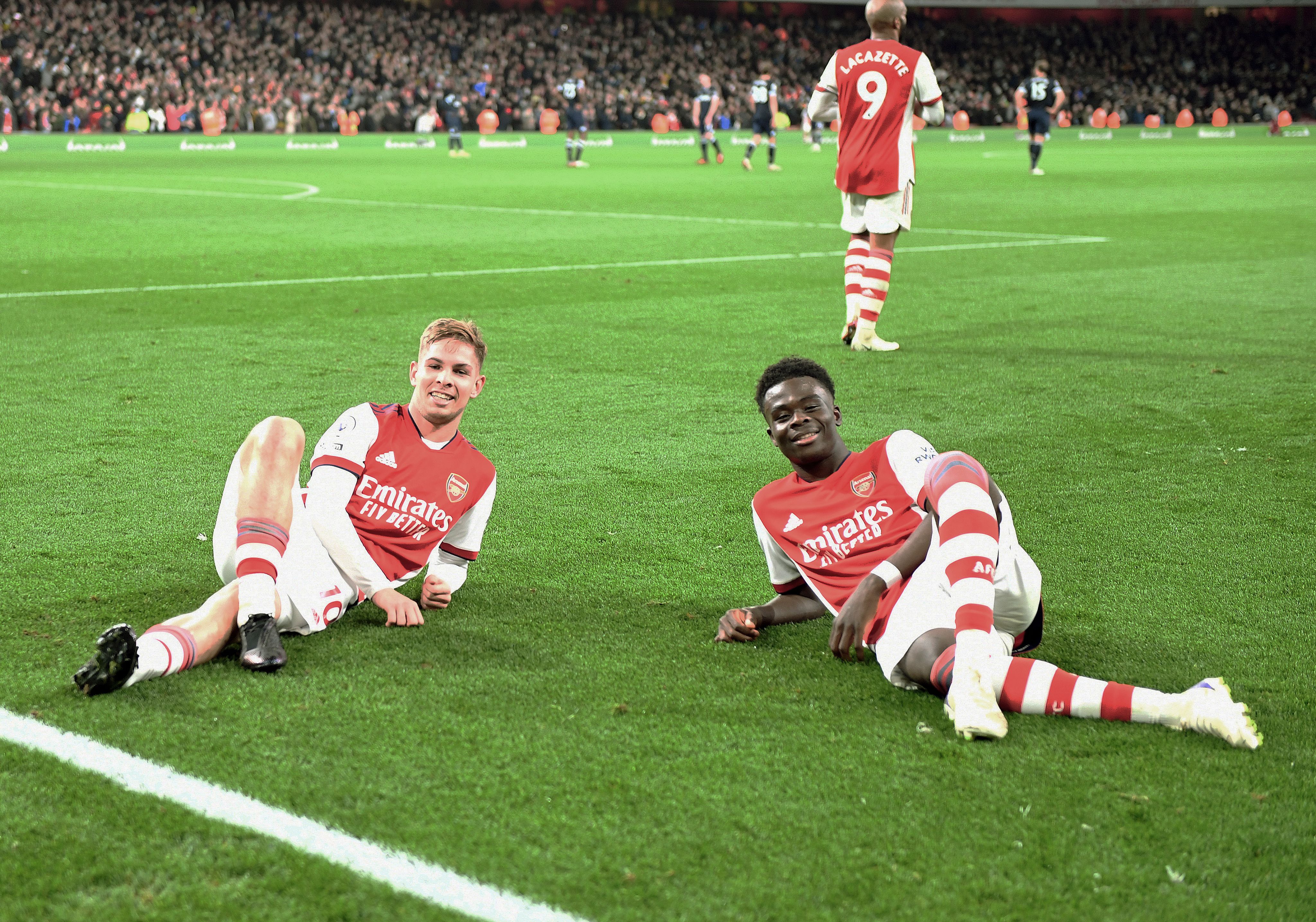 Emile Smith Rowe and Bukayo Saka celebrate the second Arsenal goal against West Ham United at Emirates Stadium in December 2021 by laying on the pitch