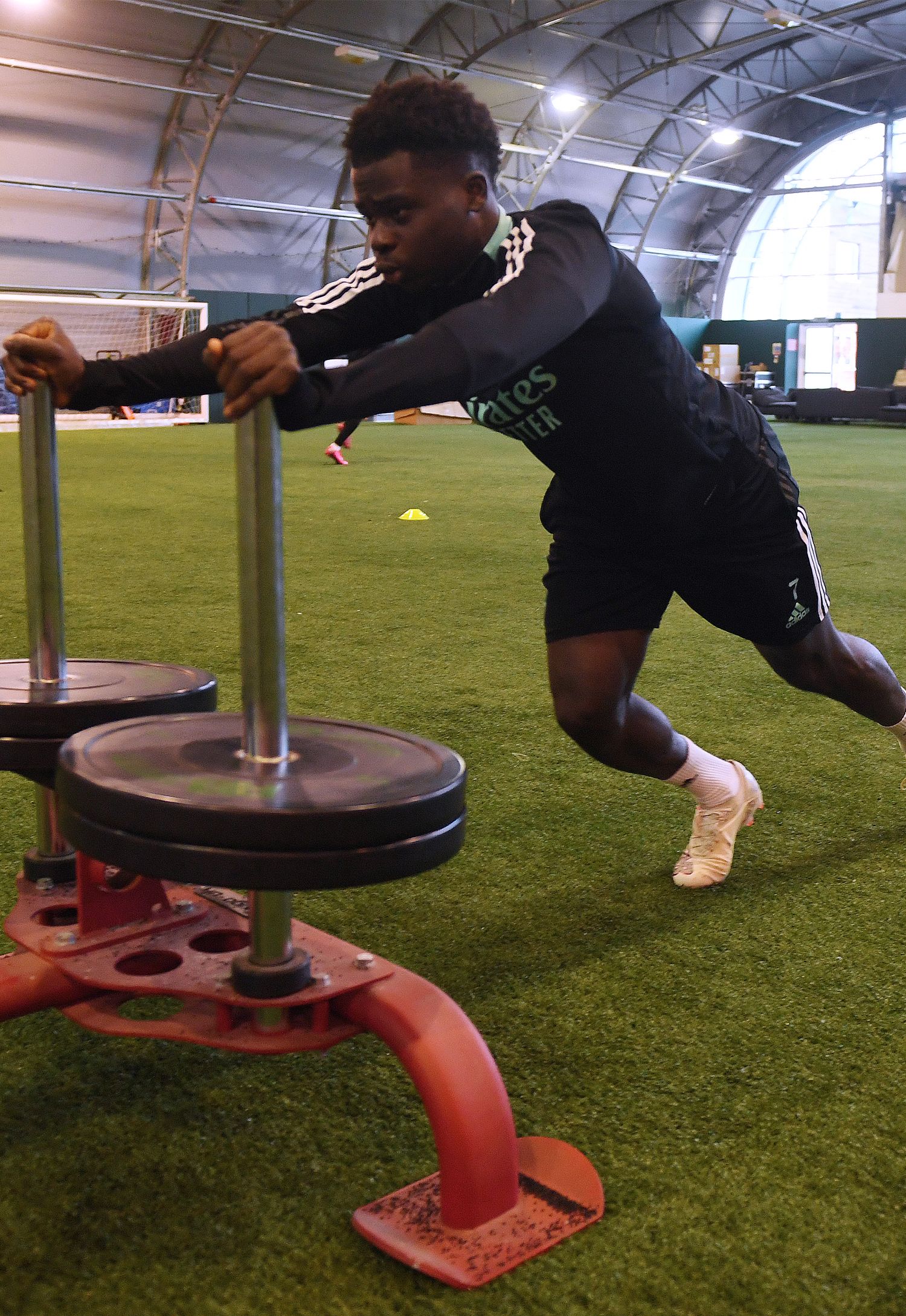 Bukayo Saka pushing weights in the indoor hall at the training ground